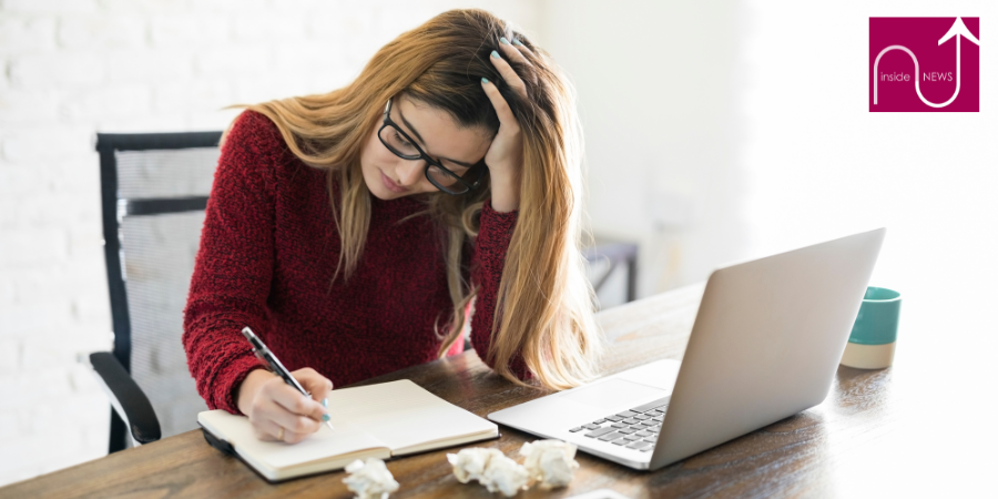 lady writing a book next to laptop